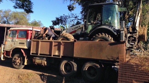 Gear being loaded onto the tip truck tray in late afternoon light