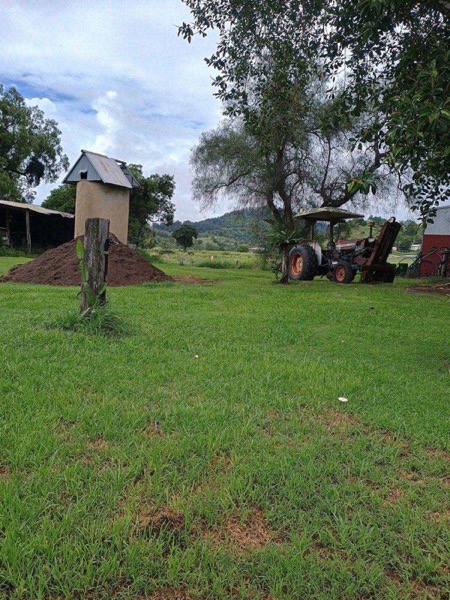 A delivered heap of topsoil beside a farm shed with the range behind